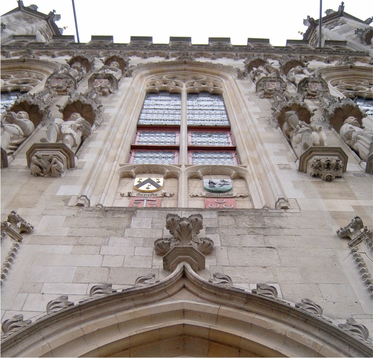 some statues are attached to a large building with a clock