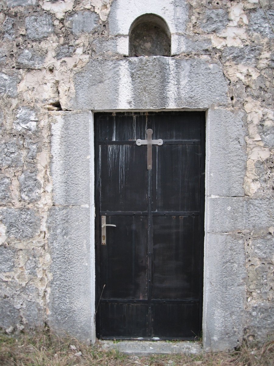 an old grey door has two crosses in the brick wall