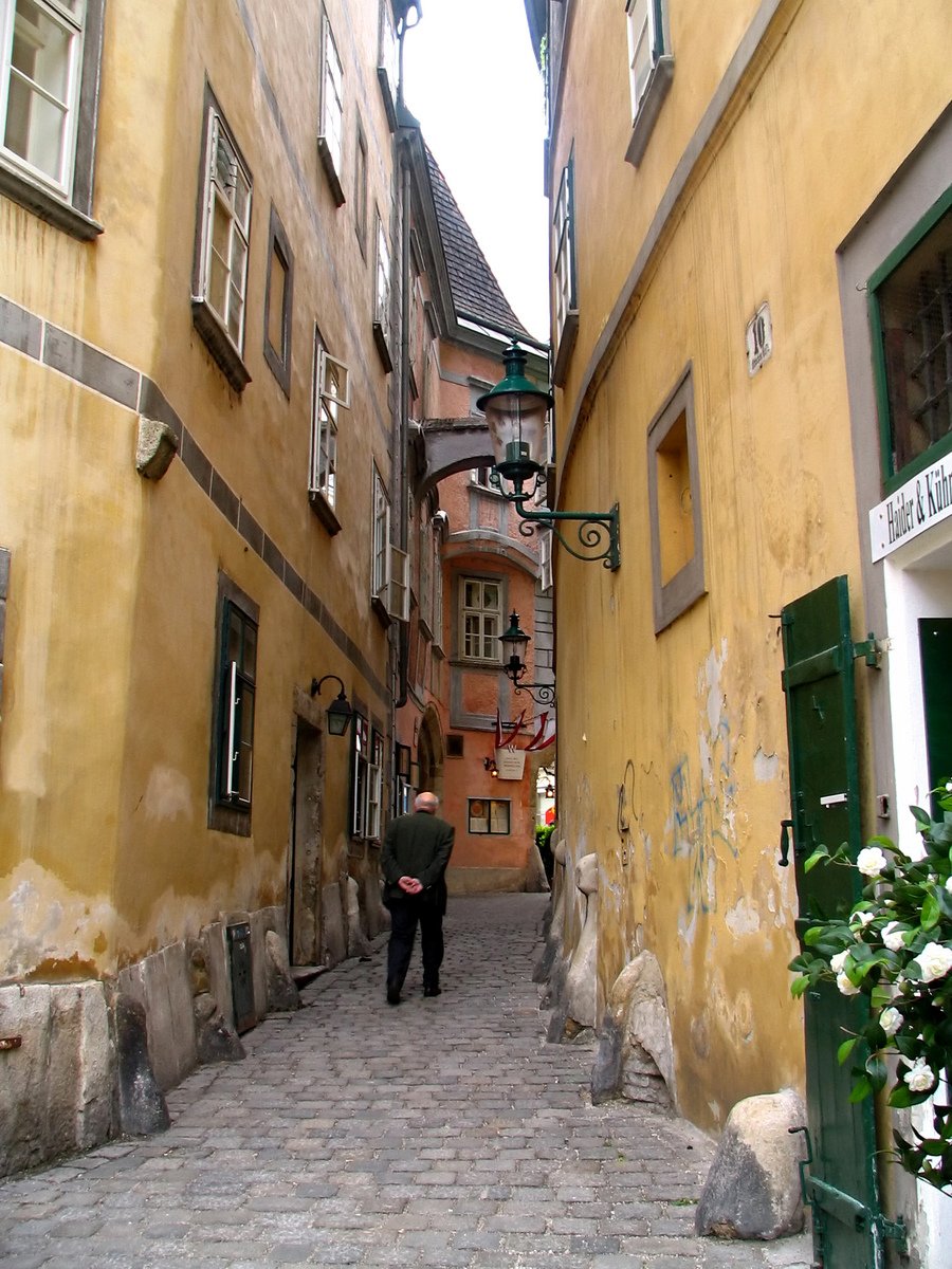 a narrow alley with two people walking in the distance