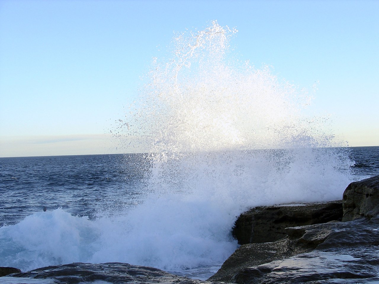 some waves in the water crashing on some rocks