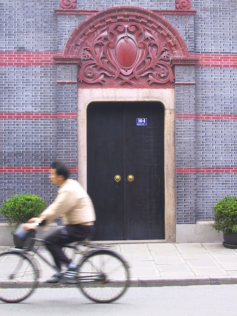 man riding his bicycle past a door and entry way