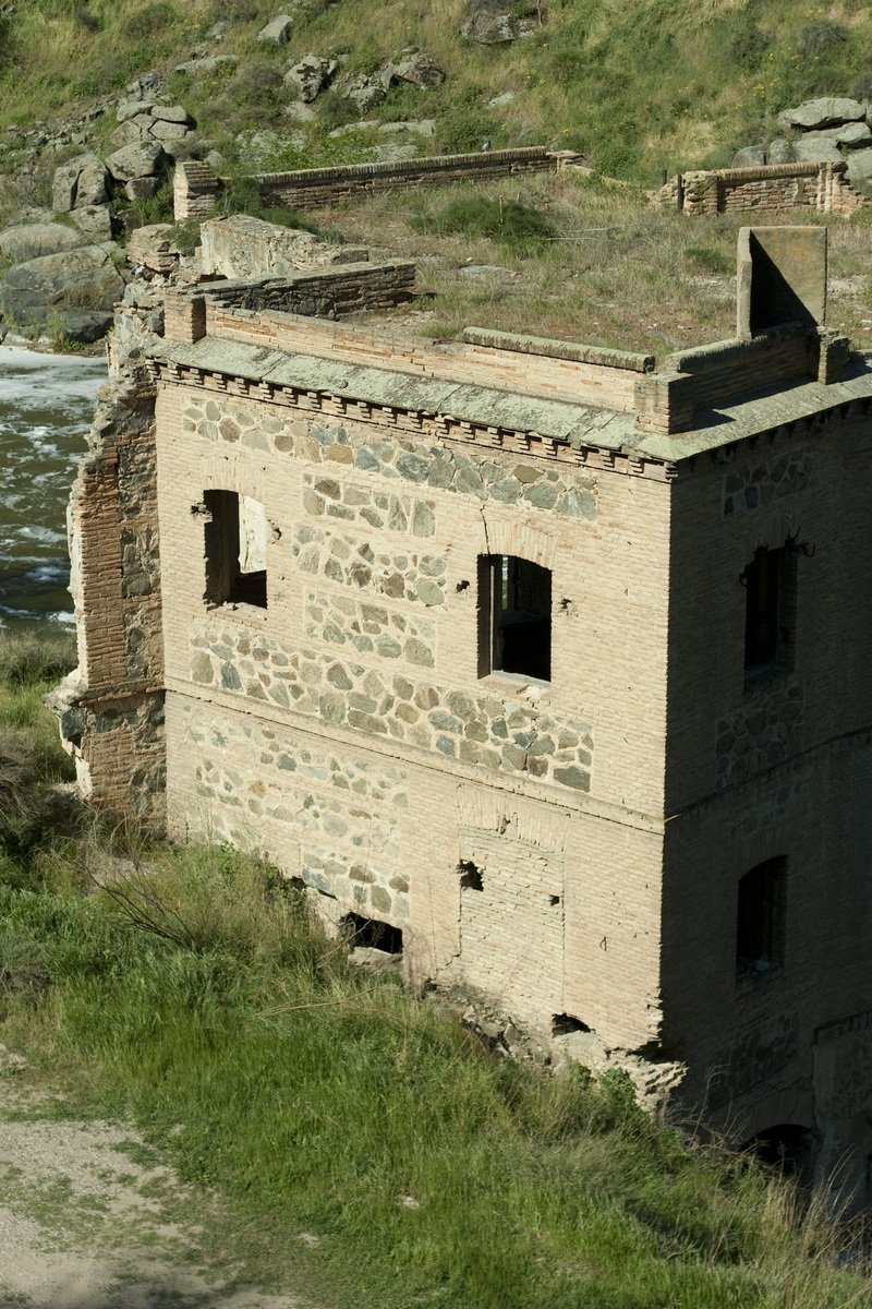 a building with a clock on top of it sitting next to the river