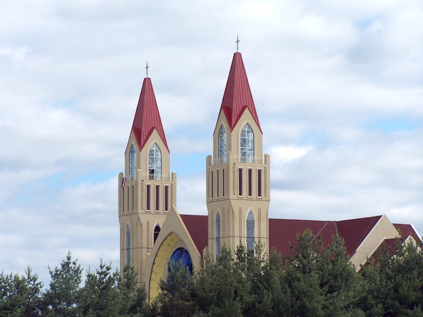 there is a tall church with red steeples surrounded by trees