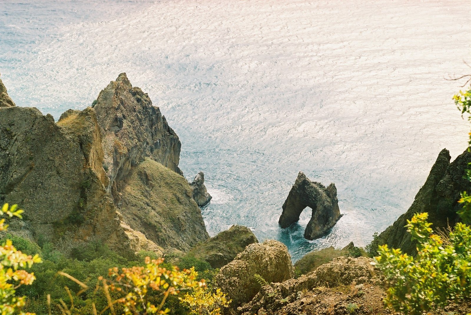 a group of rocks on the water with one rock sticking out to the ocean