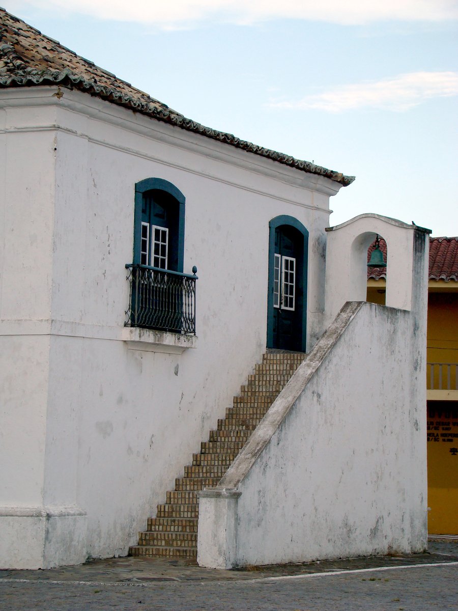 an old white building with two windows and steps up to it