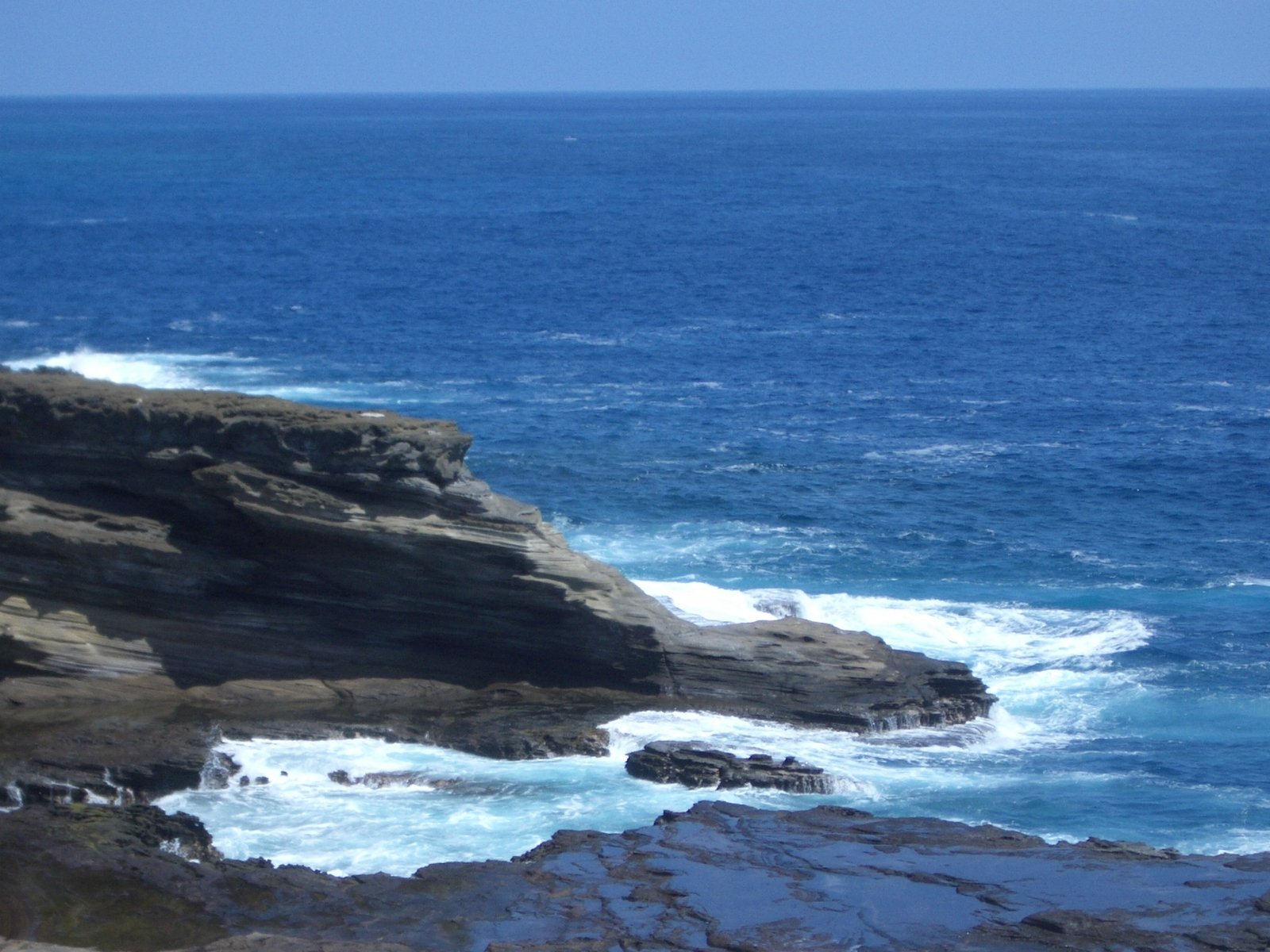 a rocky cliff with the ocean and rocks below it