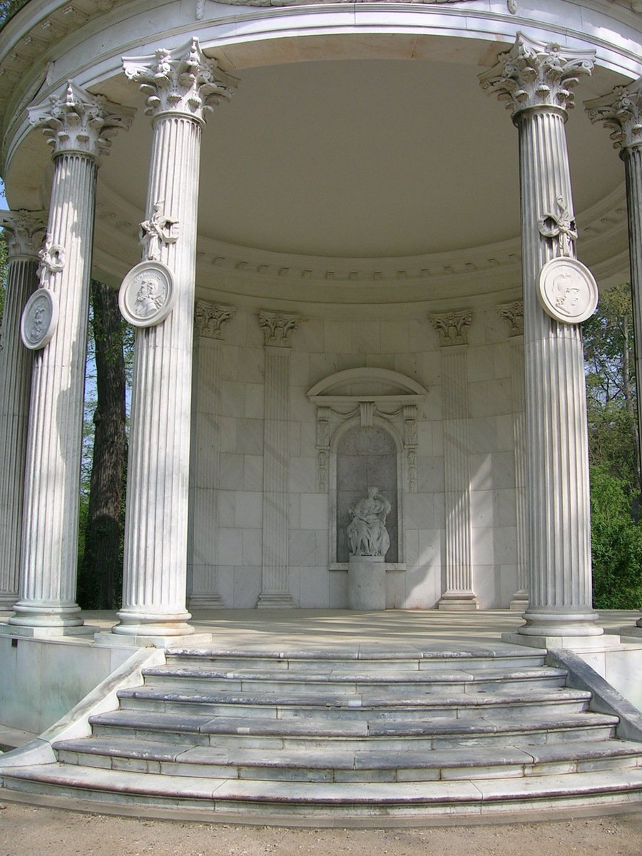 a white marble gazebo with four columns and three large statues