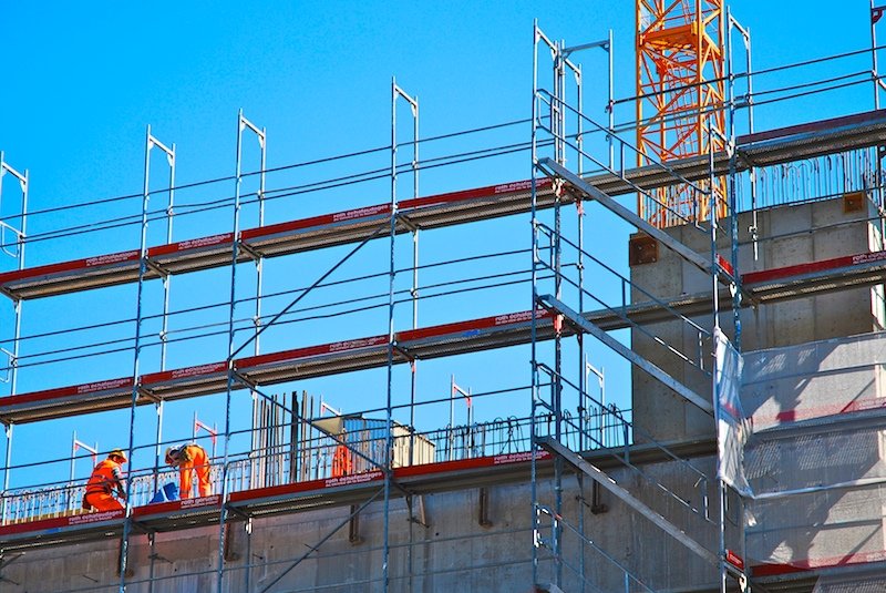 workers at the construction site preparing to erect a pipe