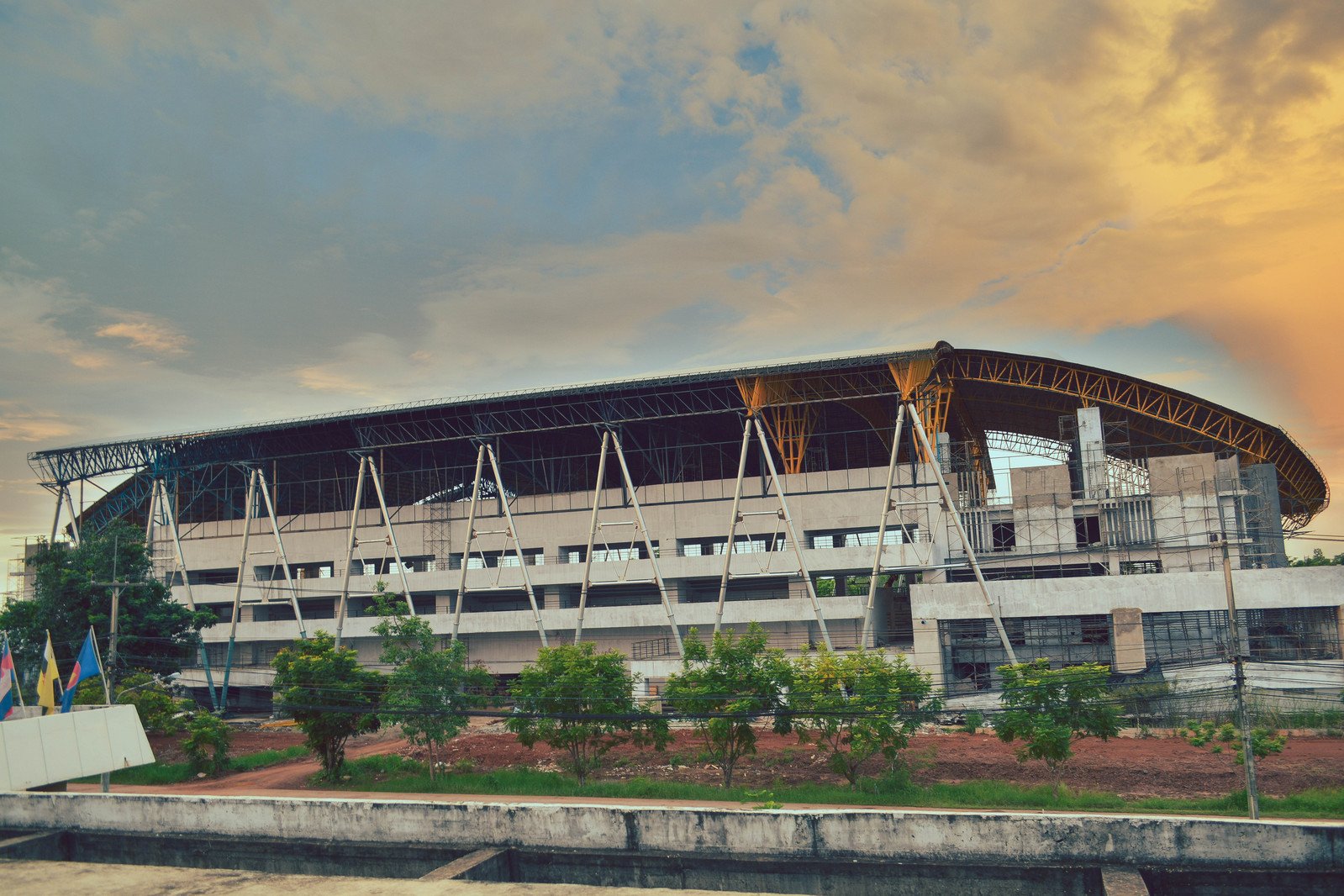 an unfinished sports stadium with an orange sky
