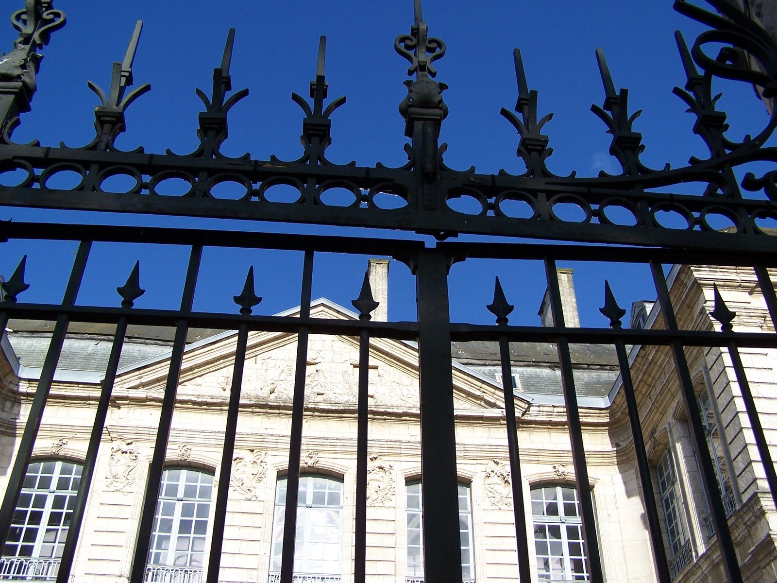 an ornate looking iron gate with the sky in the background