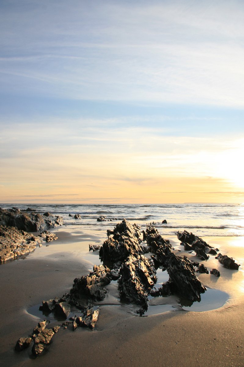 rocks in the water on a beach with blue sky