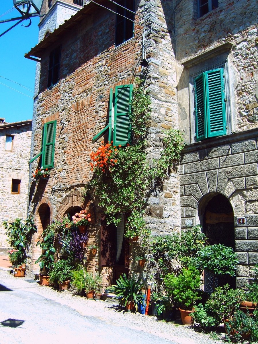 a stone building with green shutters in an alley way