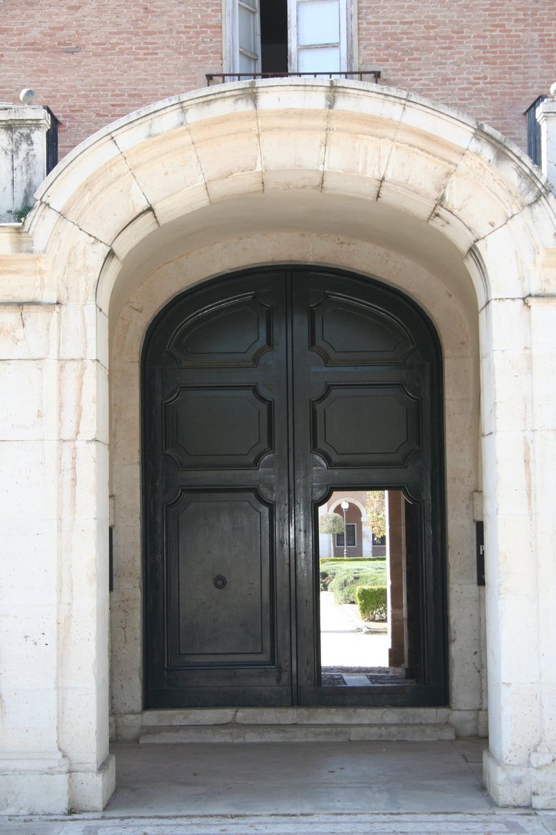 a stone building with an archway and black doors