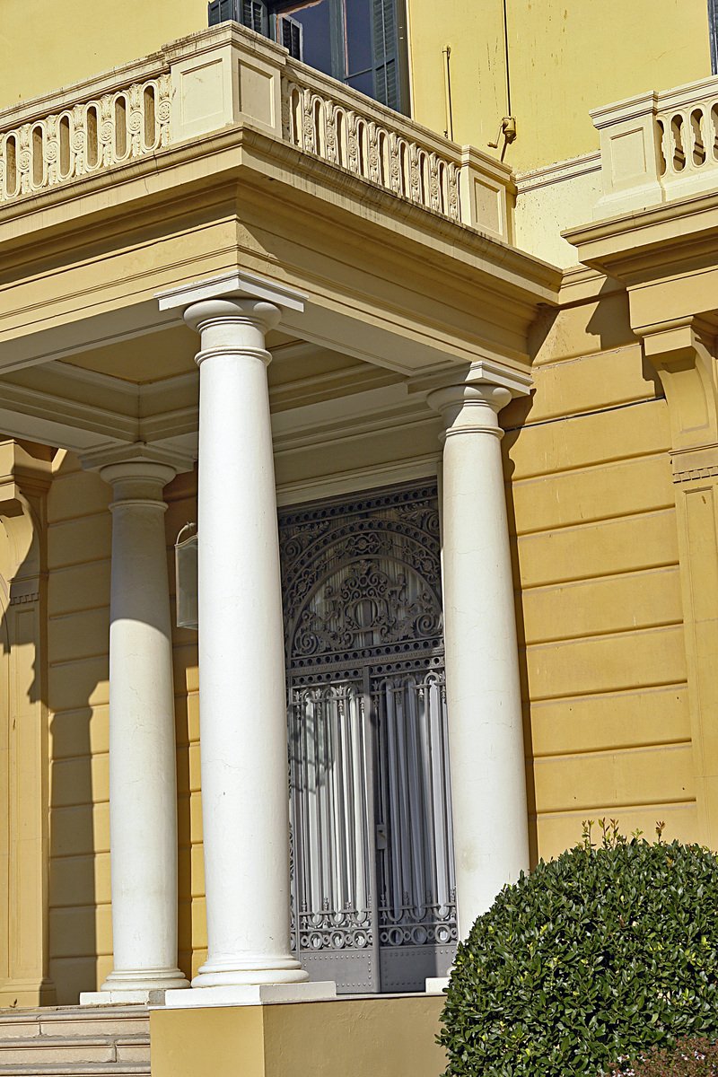 an ornate yellow building with columns and shutters