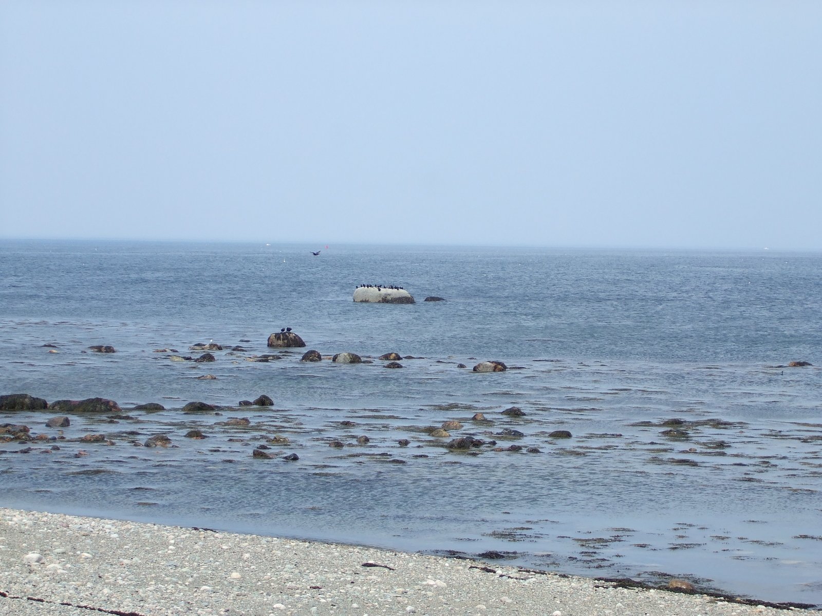 a boat traveling across the ocean in a light blue sky