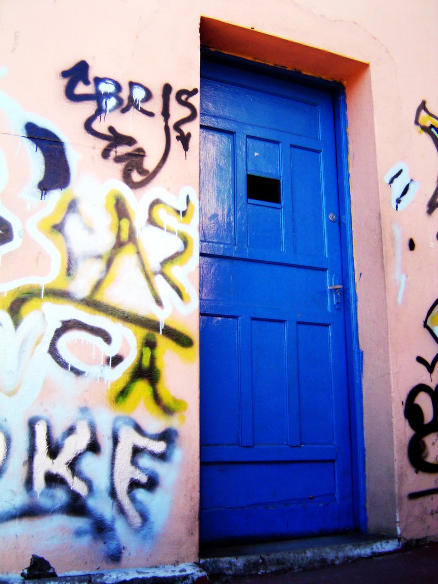 an entrance that has been painted blue and is decorated with graffitti