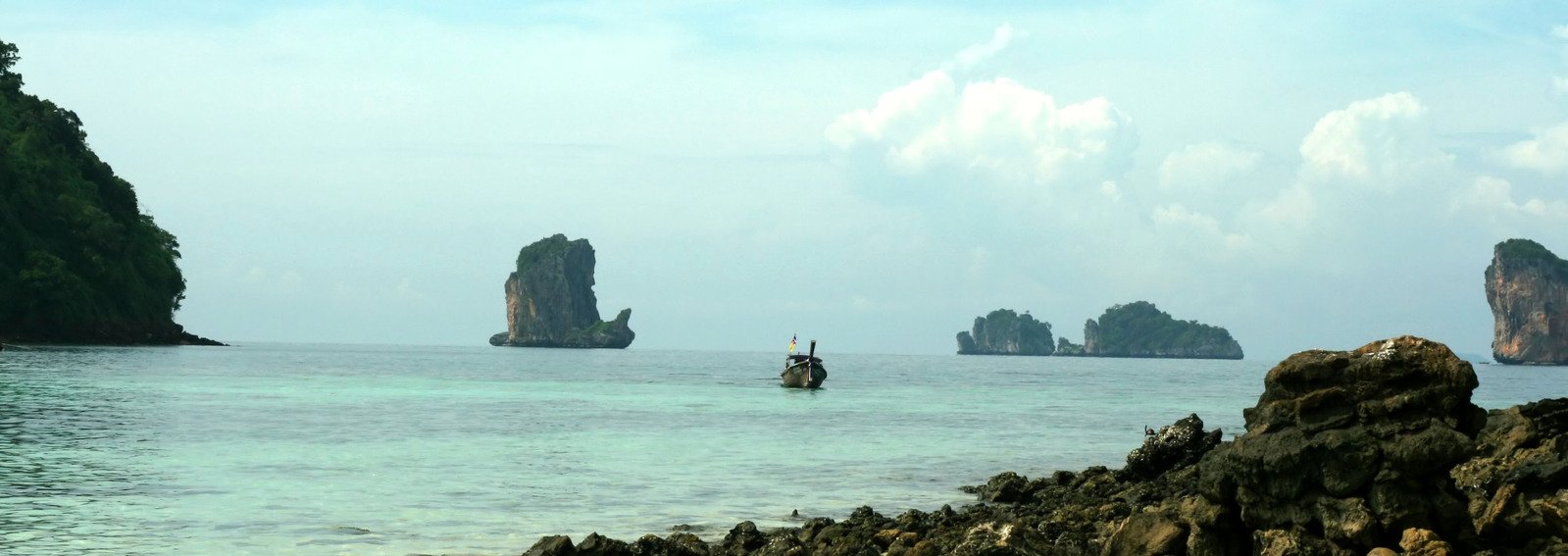a small boat out on the water near several small rocks
