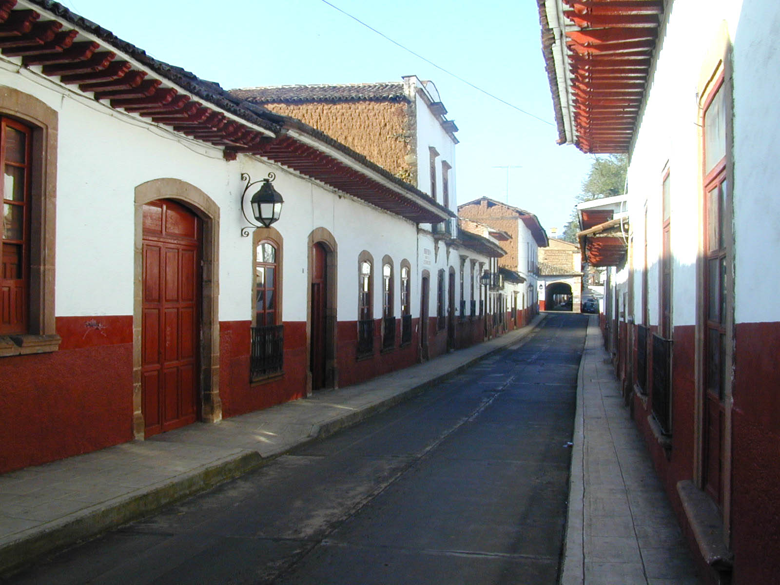 a sidewalk between two white buildings with red trim