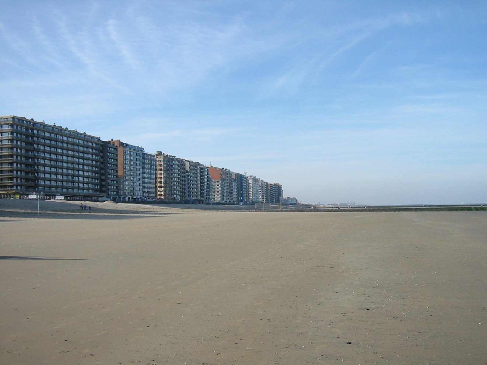 several large building on a sandy beach next to a body of water