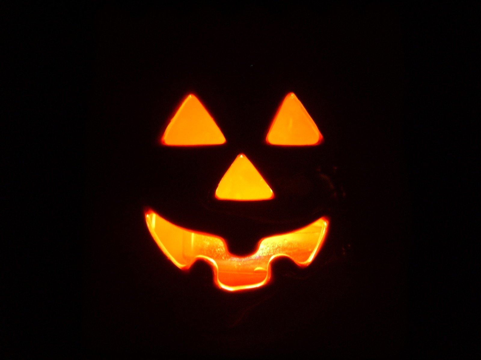 an illuminated pumpkin with a grinning jack - o - lantern face