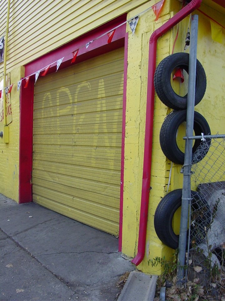 a yellow garage with a large tire next to it
