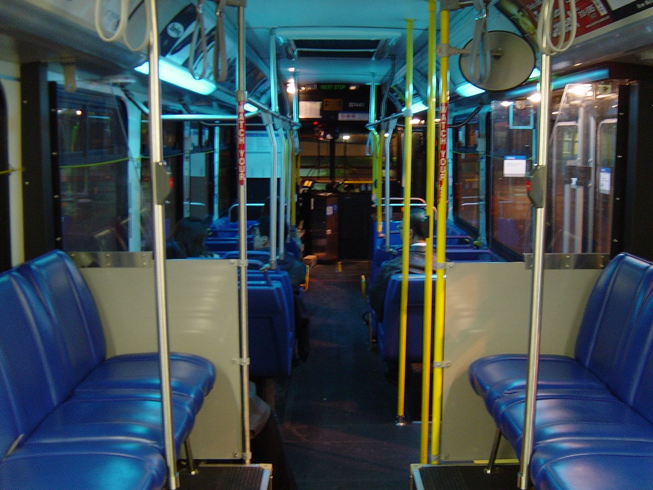 an empty blue train seats with neon yellow poles on each