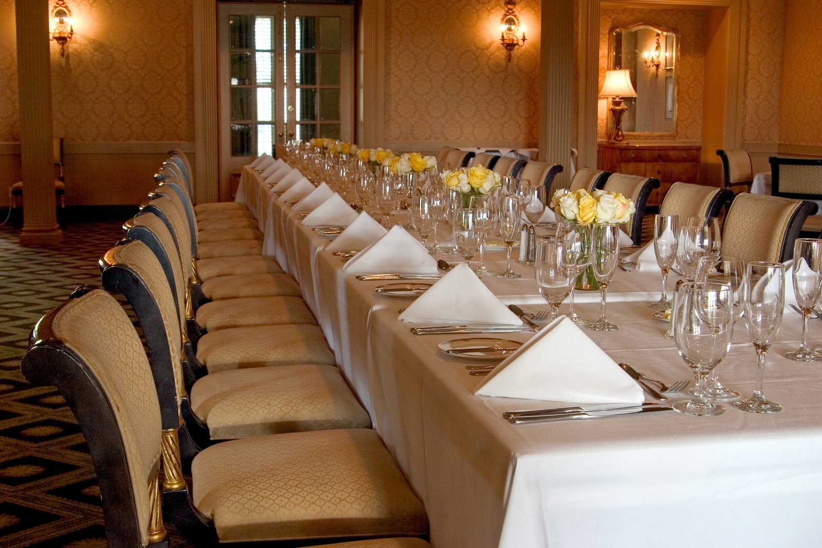 a dining room with long tables set with wine glasses