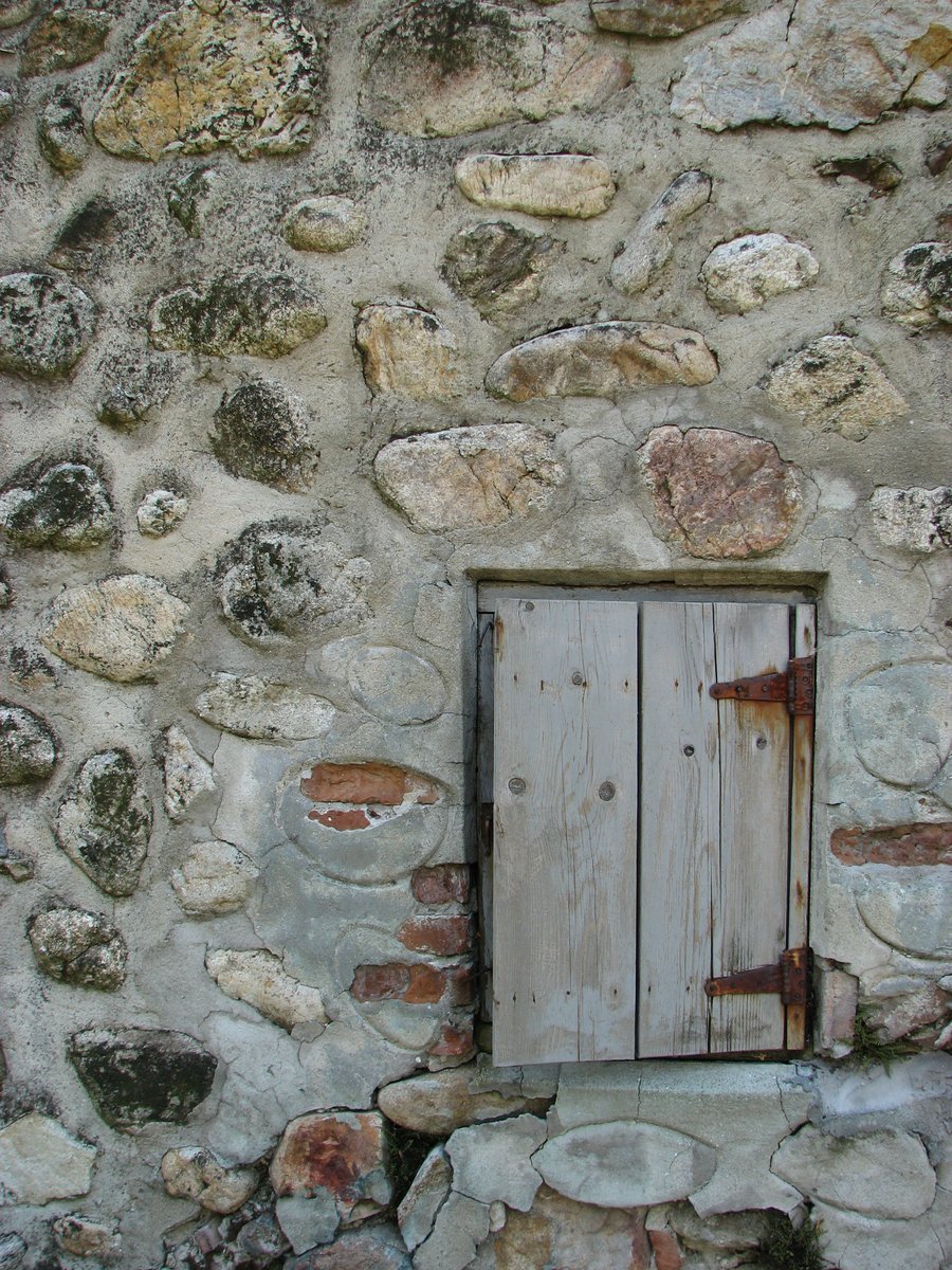 the wood in the door is leaning against the stone wall