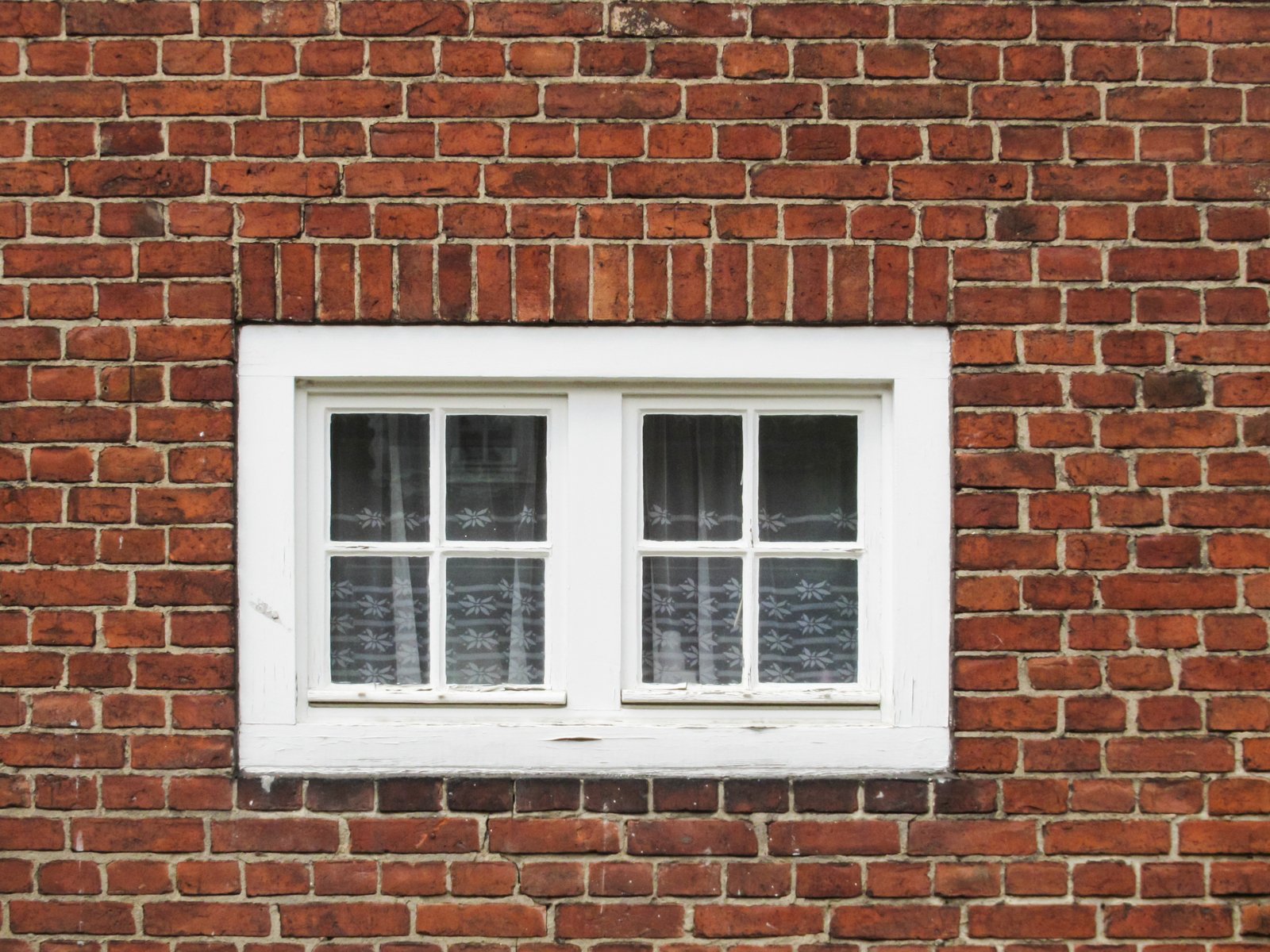 a white window sitting on the side of a red brick building
