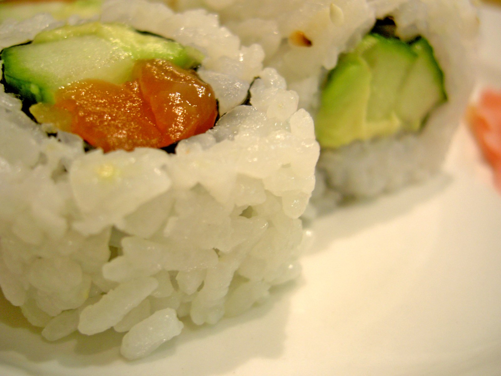 pieces of sushi are covered with orange sauce and cucumber
