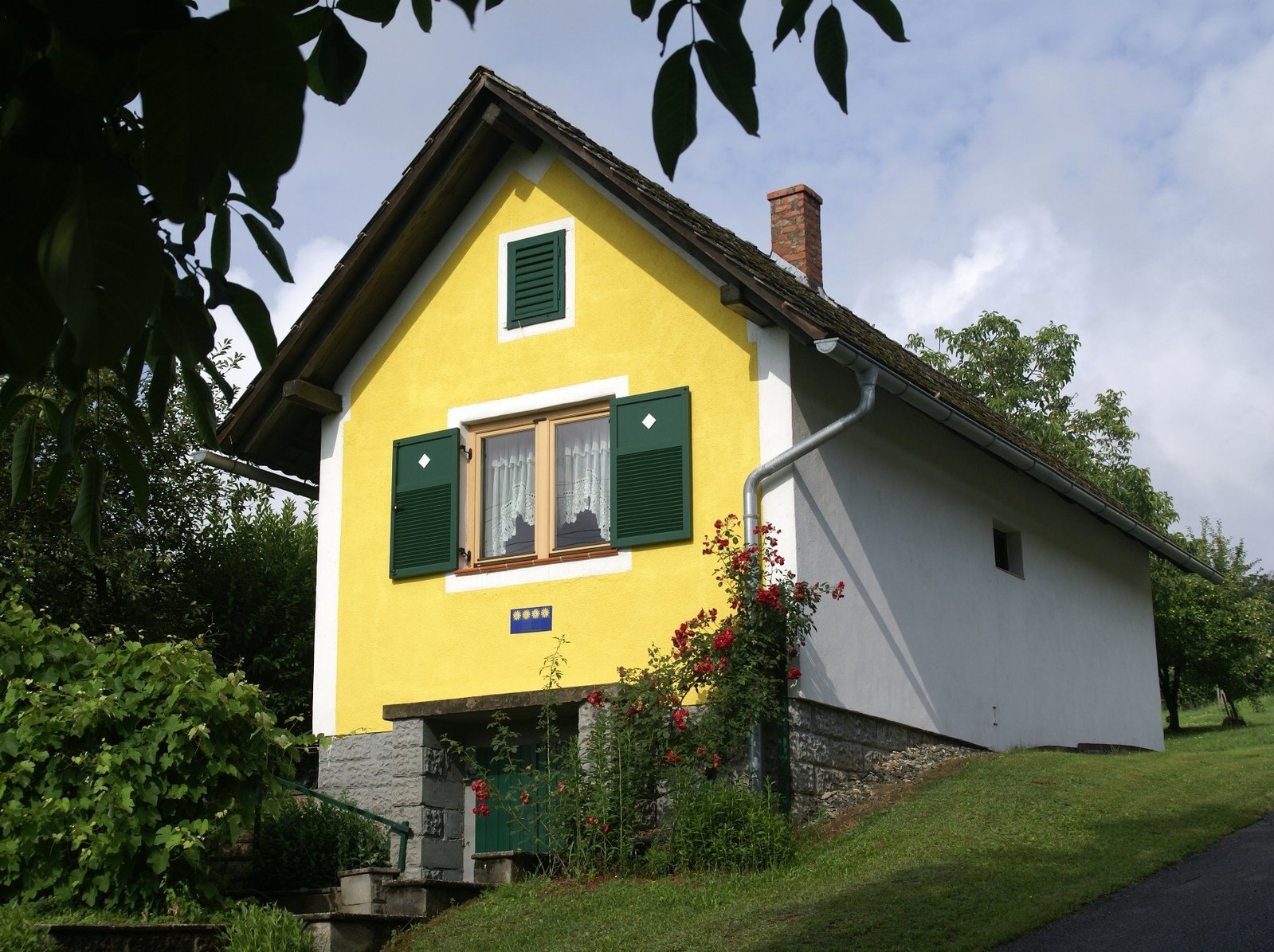 an image of a yellow house in the middle of a garden