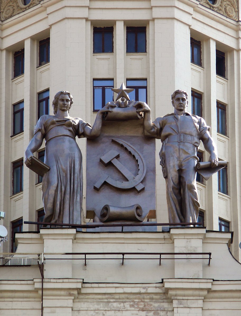 two statues are posed next to an arm - scale shield