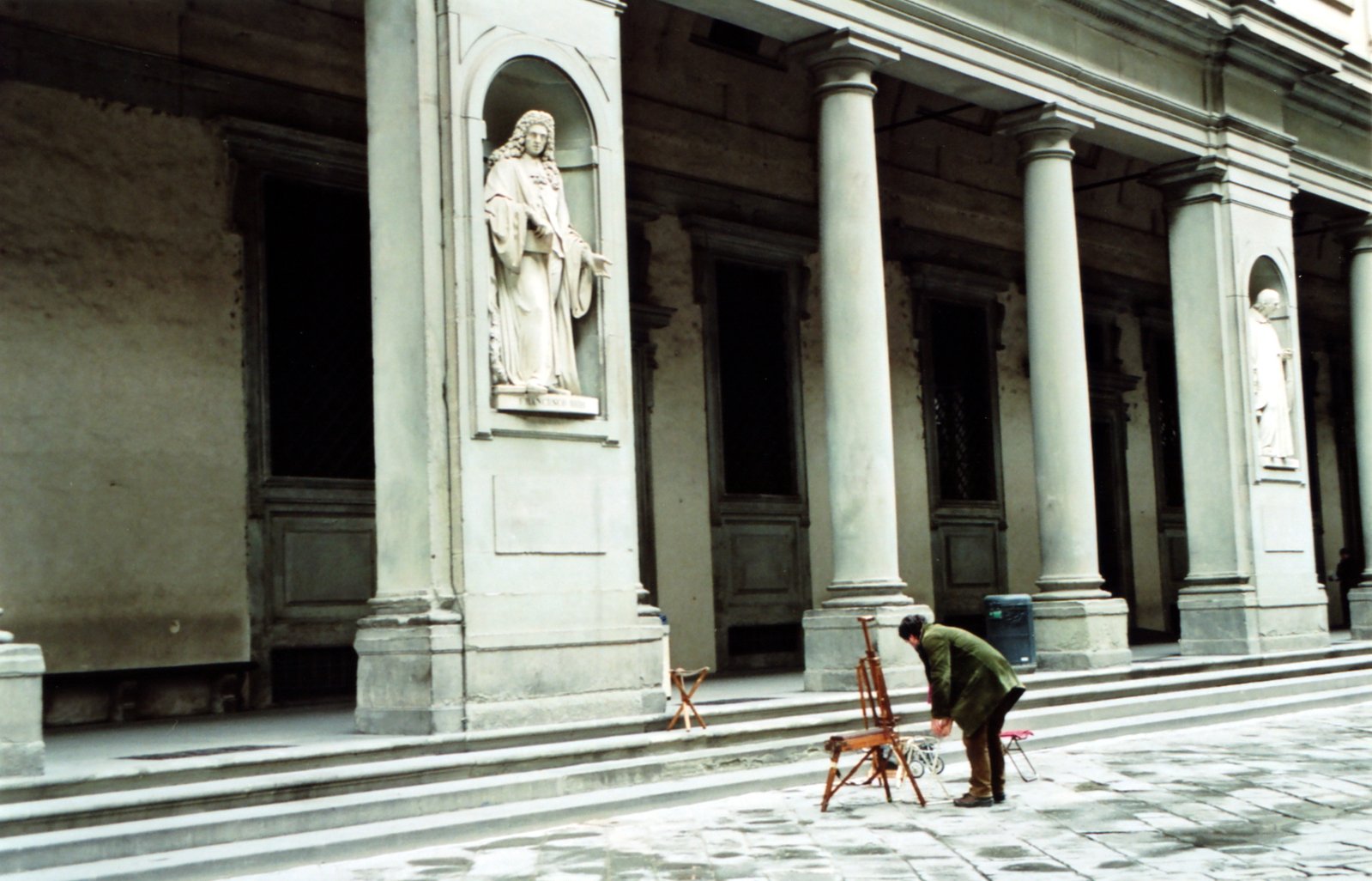 a man working in front of an old building with a statue