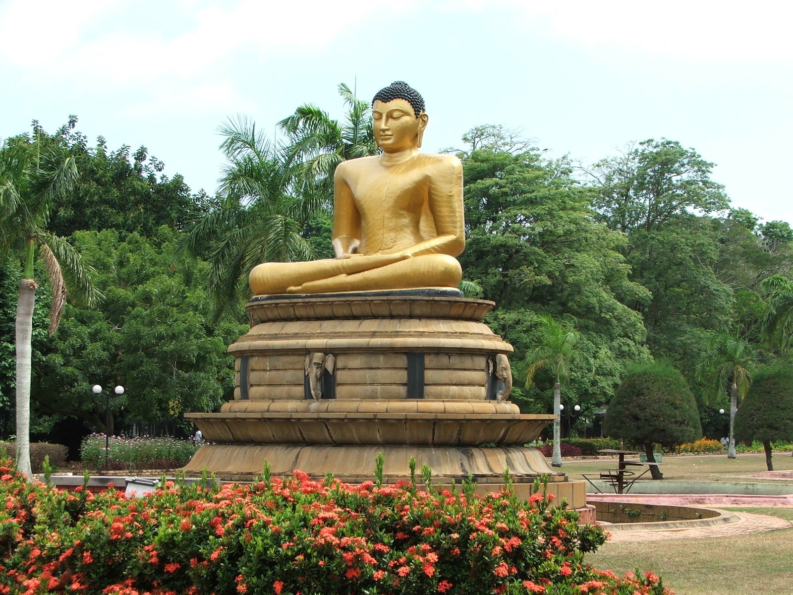 there is a large buddha statue sitting in the middle of a flower garden