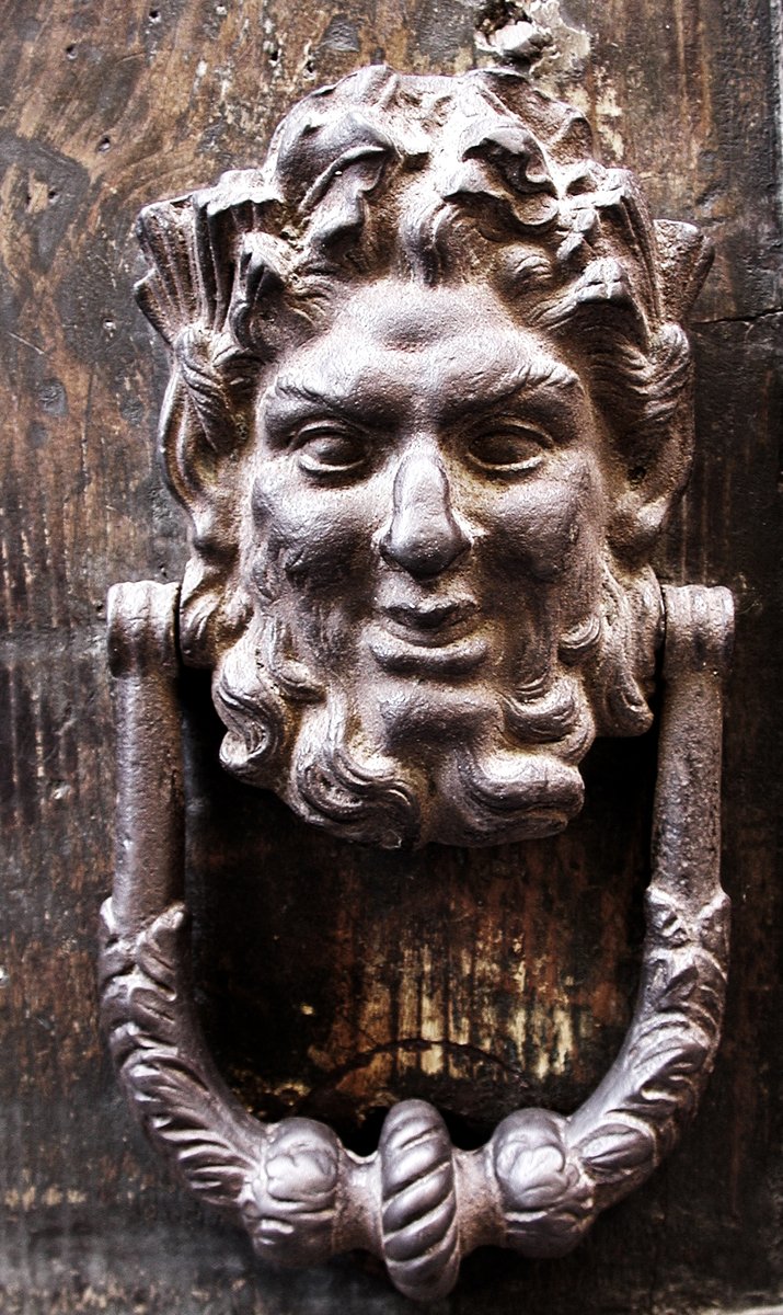 the face of a man on an old wooden door is painted gray