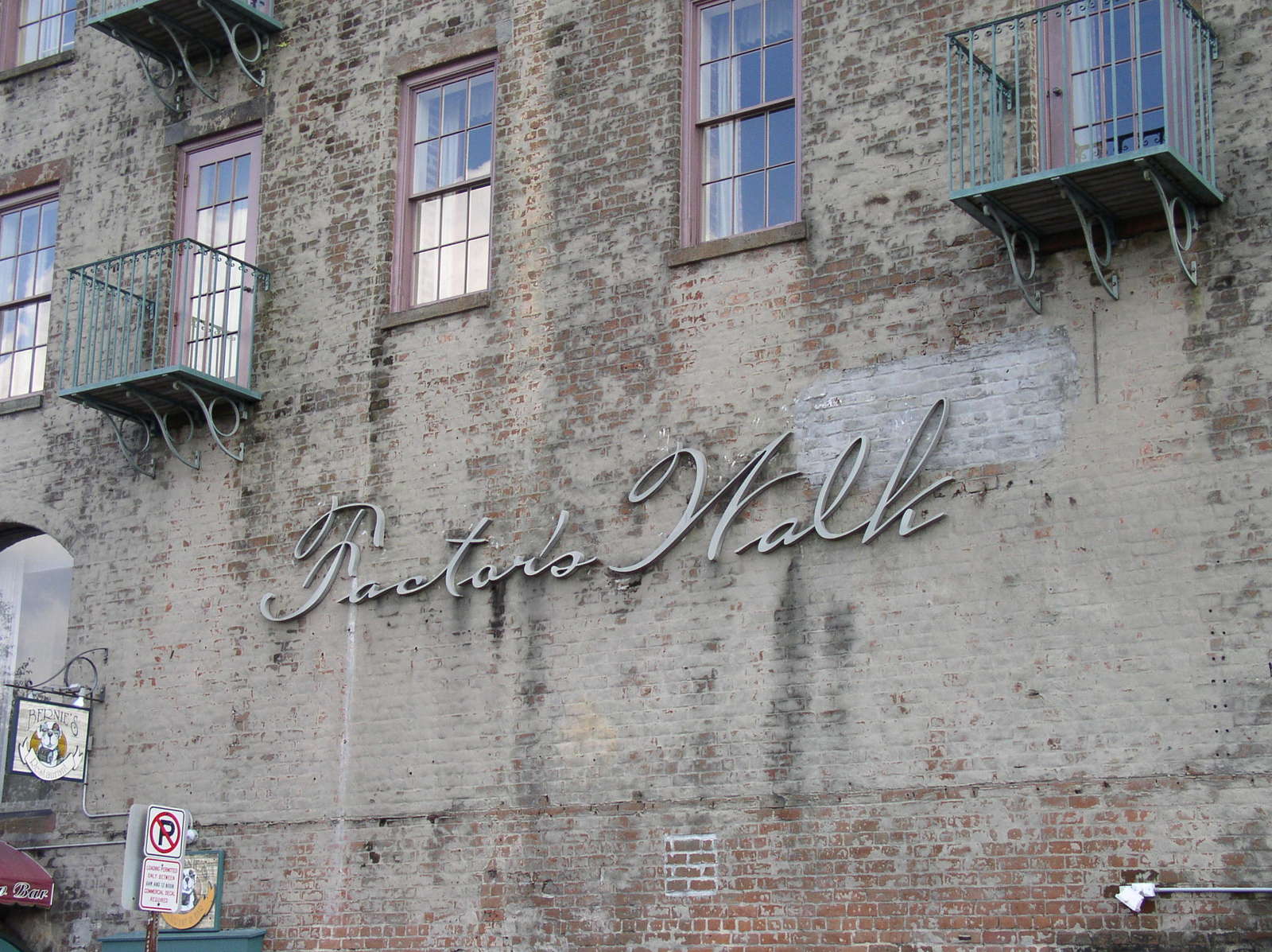 a close up of the outside of a brick building with large windows and an arched sign on the outside of it