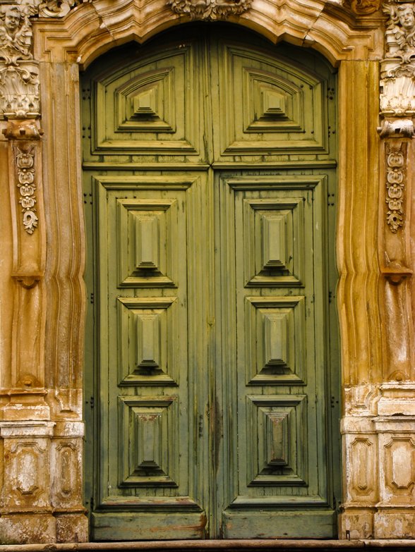 a very old green door surrounded by two massive columns