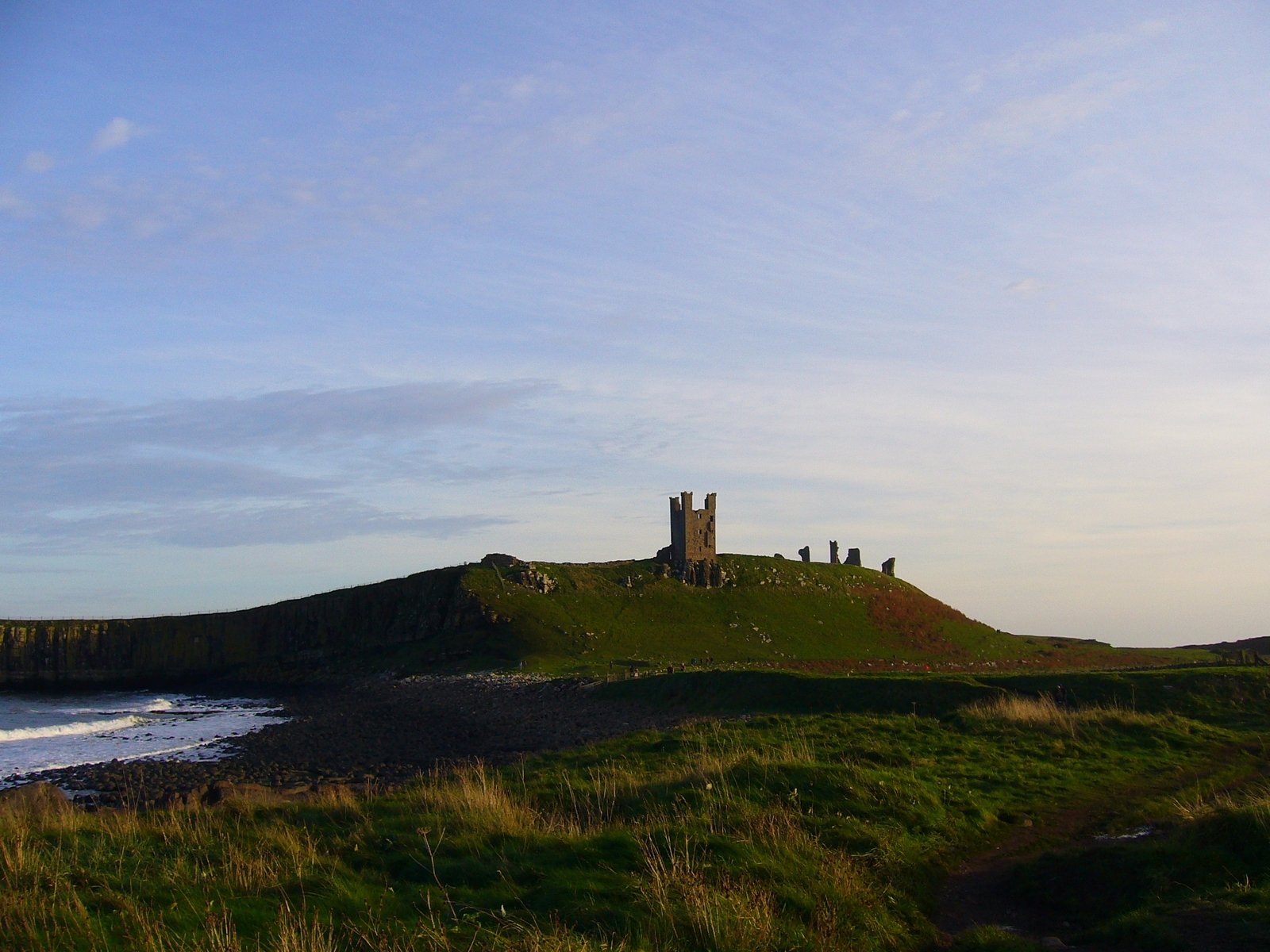 a very tall building sitting on top of a green hill