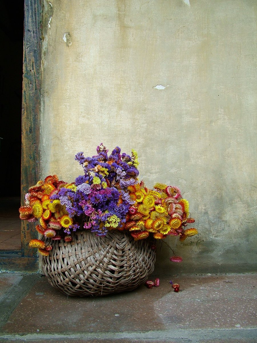 a wicker basket full of flowers with a blue flower in it