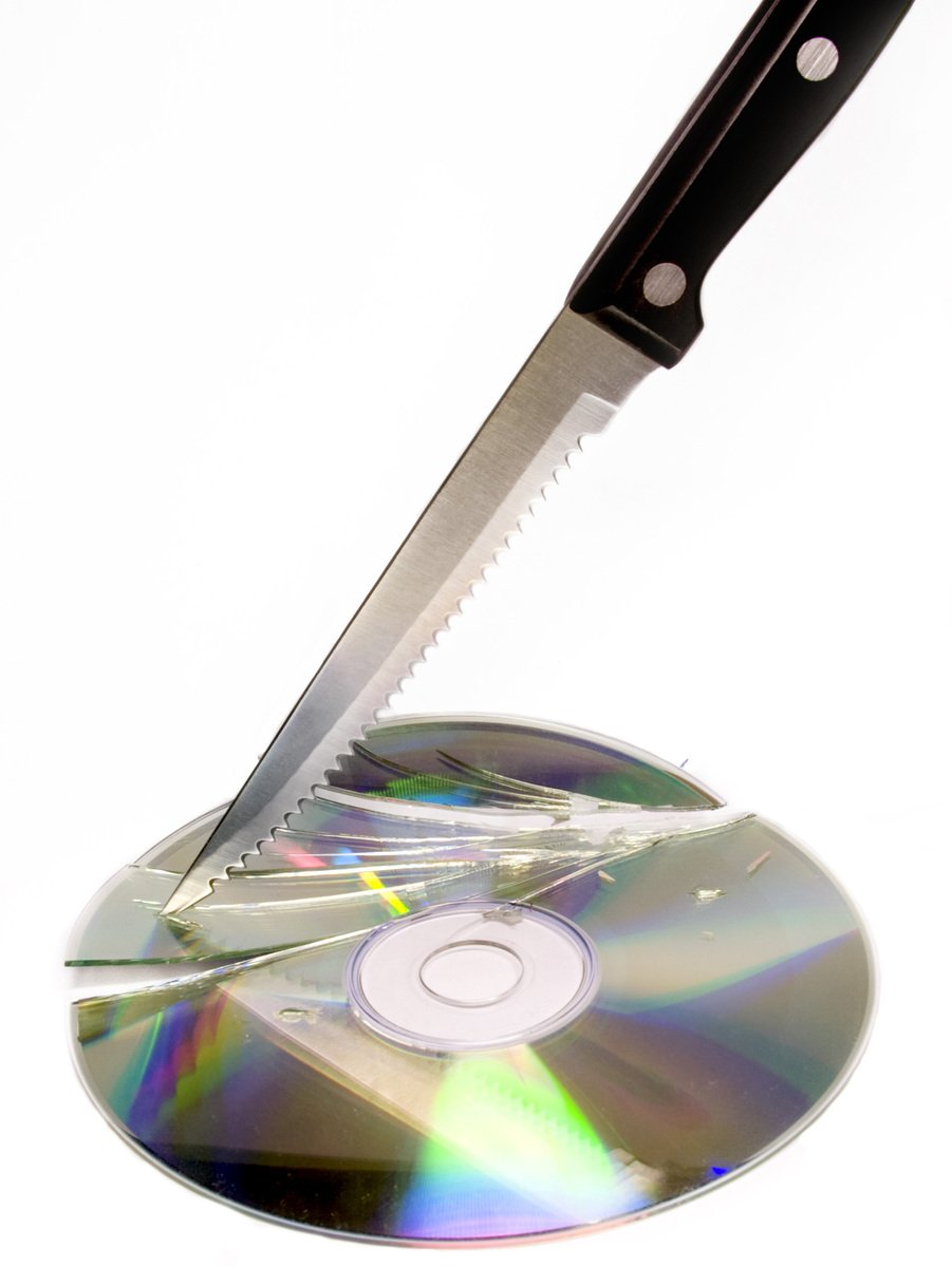 a knife is attached to a cd on a white surface