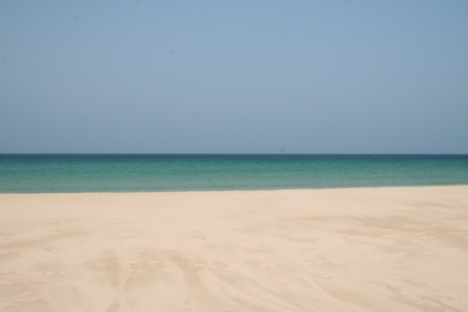 a small boat is out on the water by a large beach