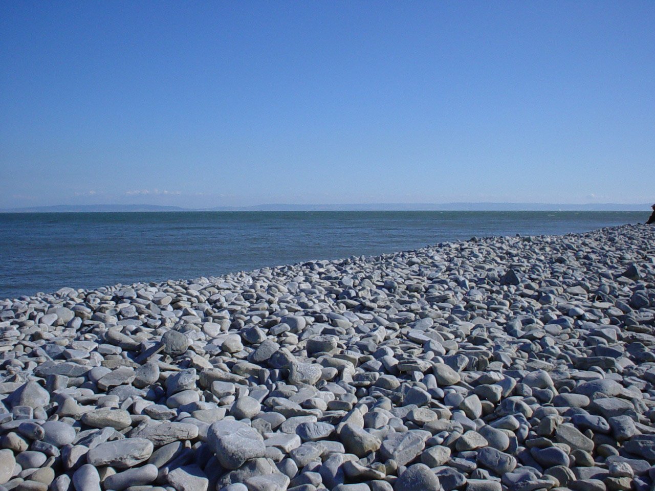 a man walking across a rocky shoreline near the ocean