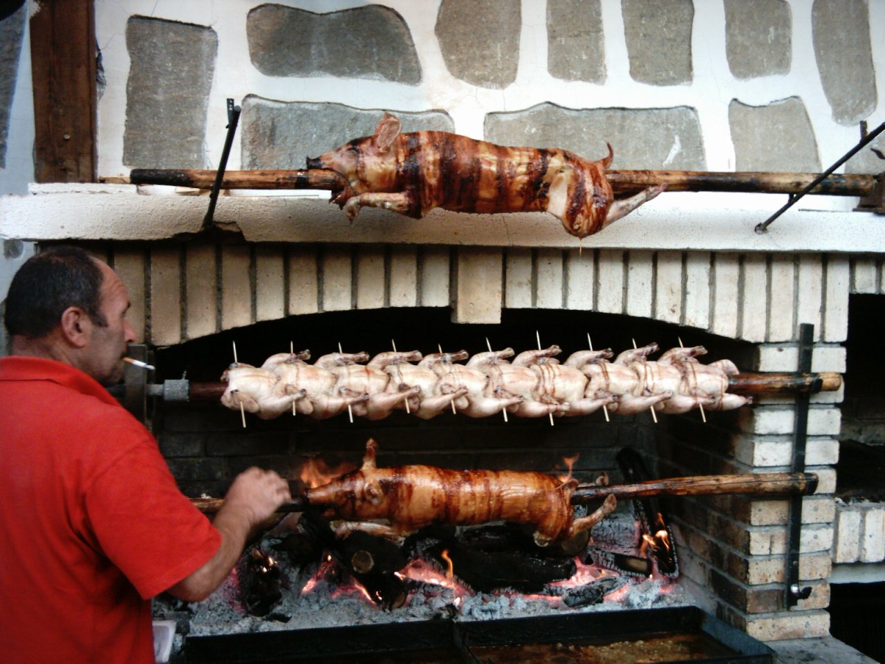 a man is grilling several meats in front of him