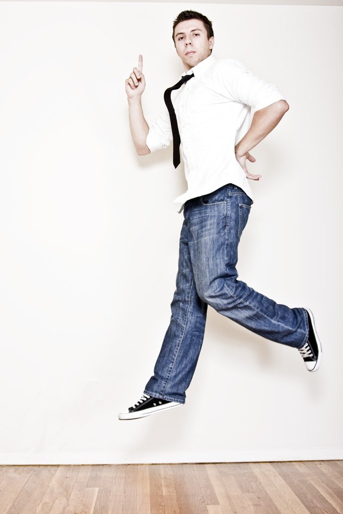man in jeans and tie leaping and dancing in the air