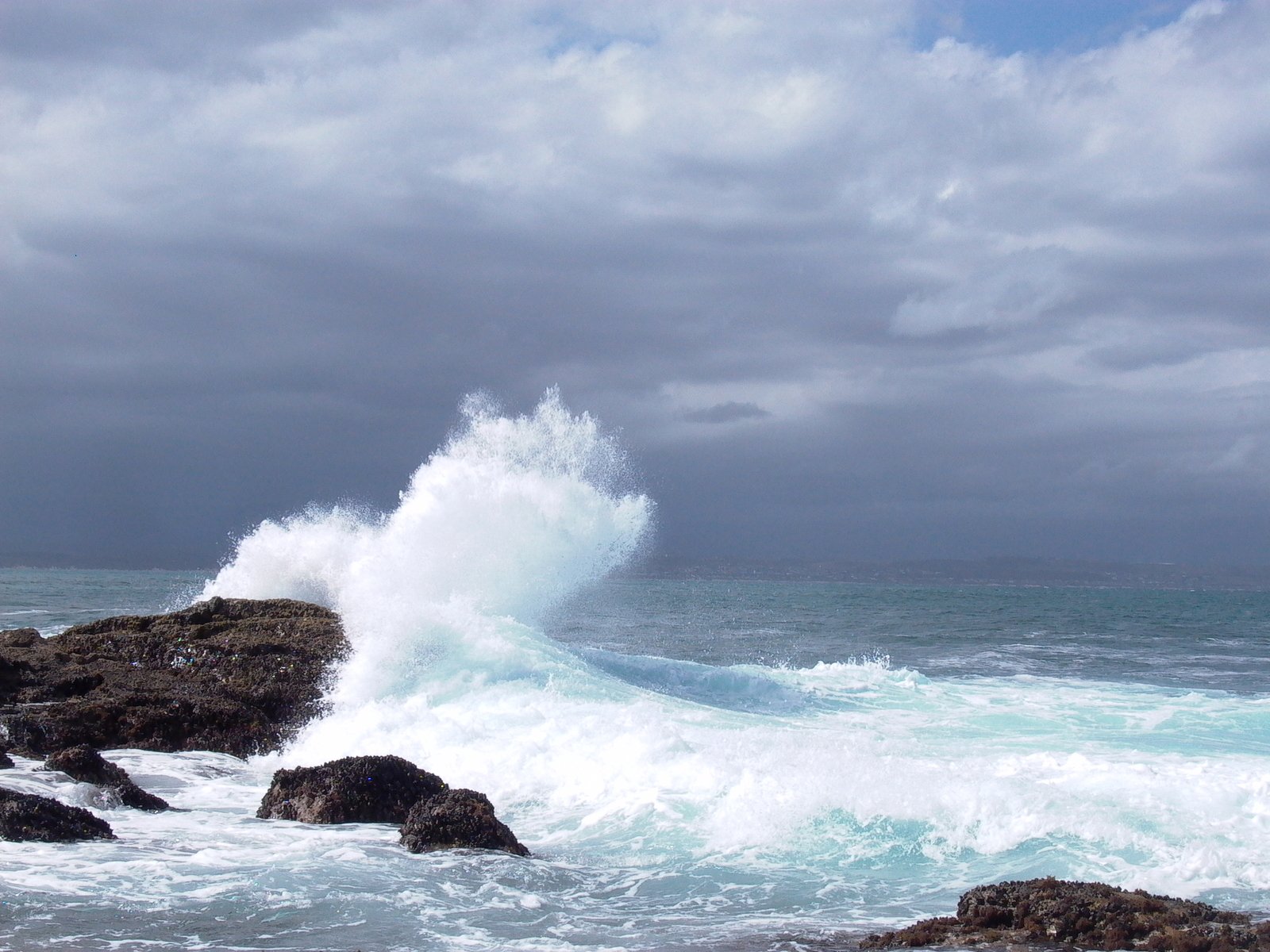 a wave hitting on some rocks in the ocean