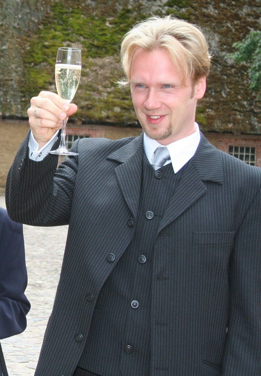 a man is wearing a suit and holding a wine glass