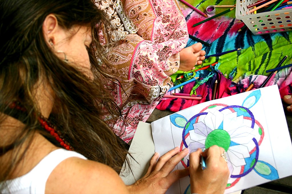 a woman drawing on paper in front of a bunch of colorful umbrellas