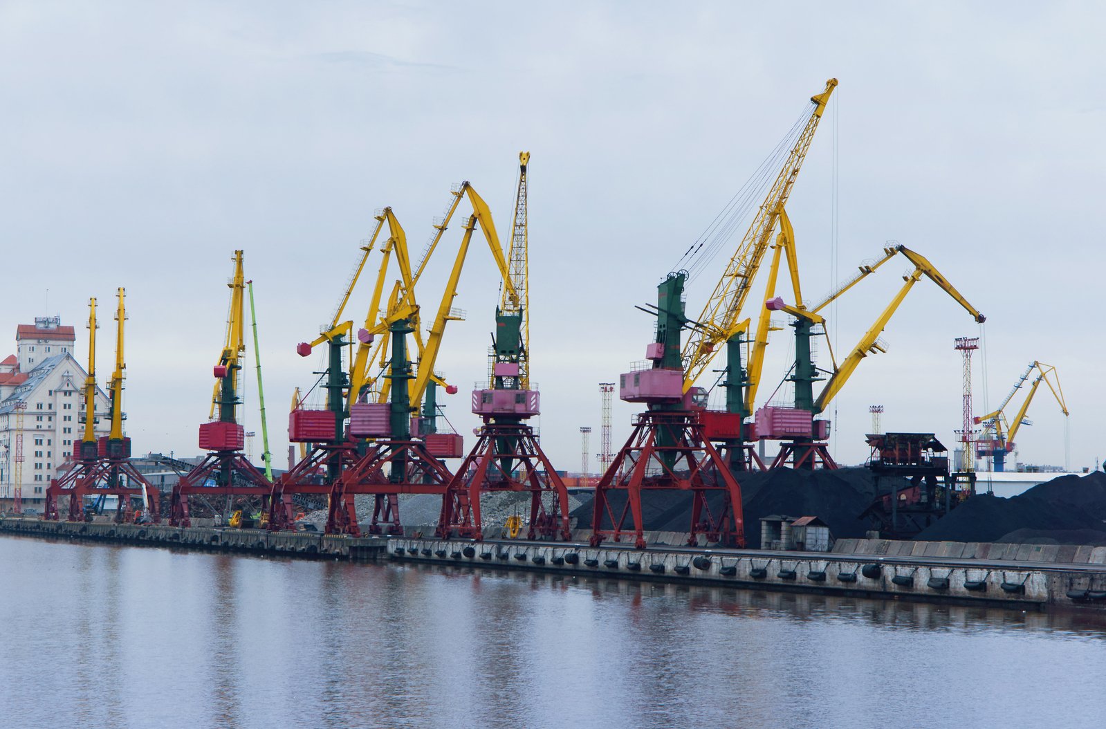 a dock holding multiple large cranes in a harbor