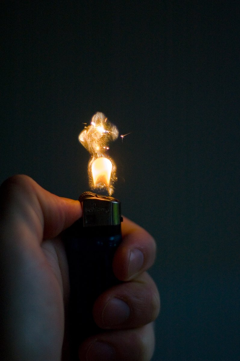someone holding a lighter with a teddy bear lit in the end