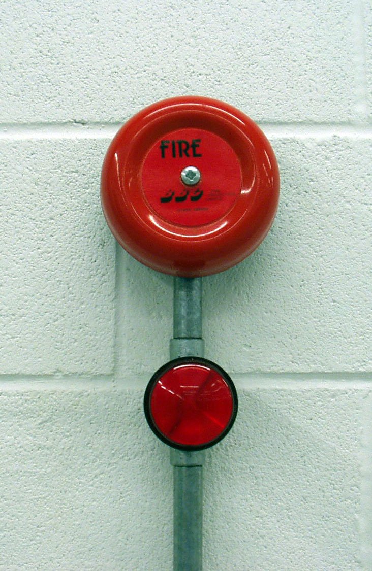 a red fire hydrant on a white wall with a sign on it